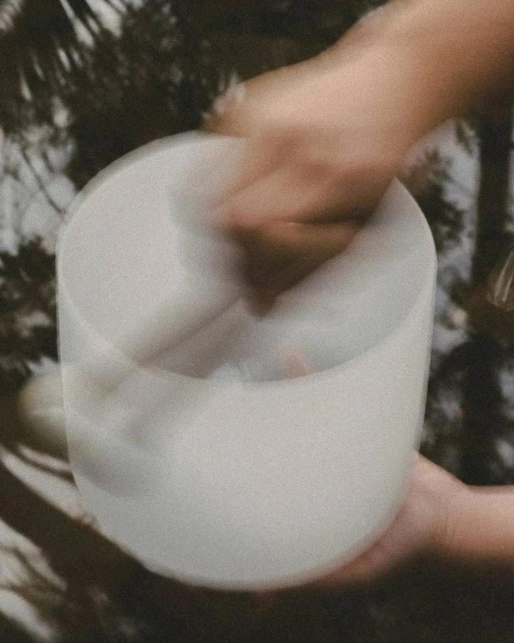 Hands playing a crystal singing bowl