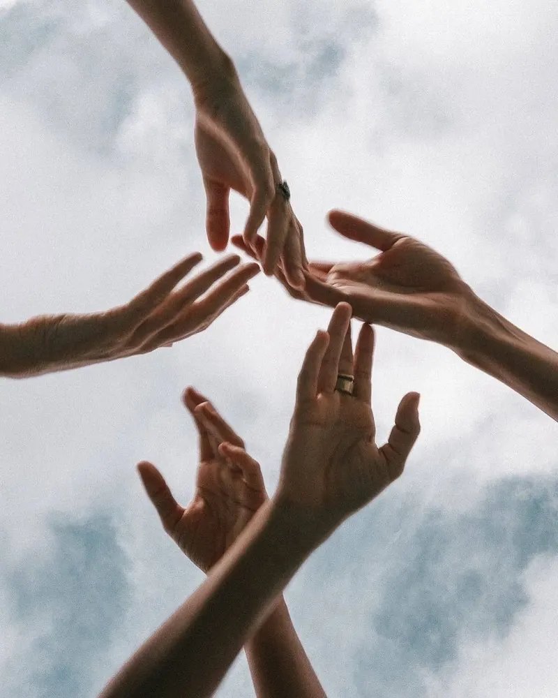 Hands reaching together toward the sky