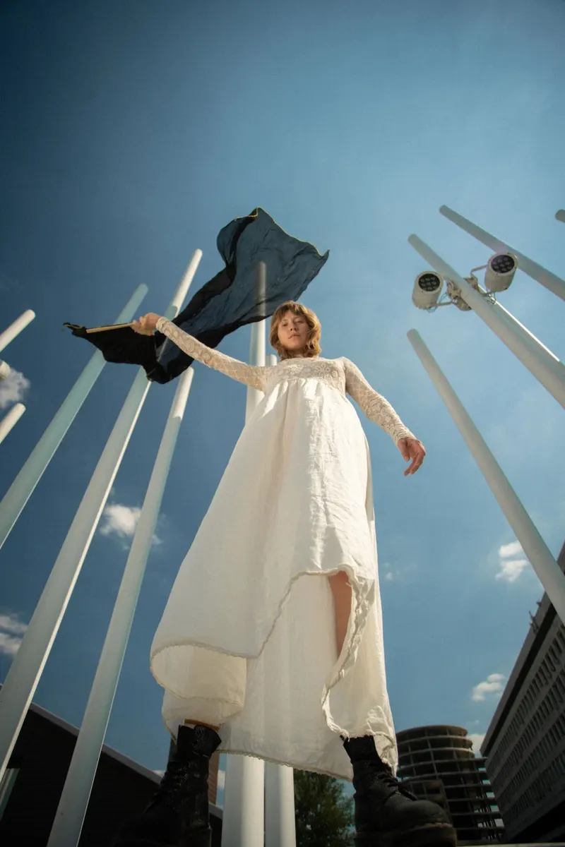 Sasha in a white dress under an open sky